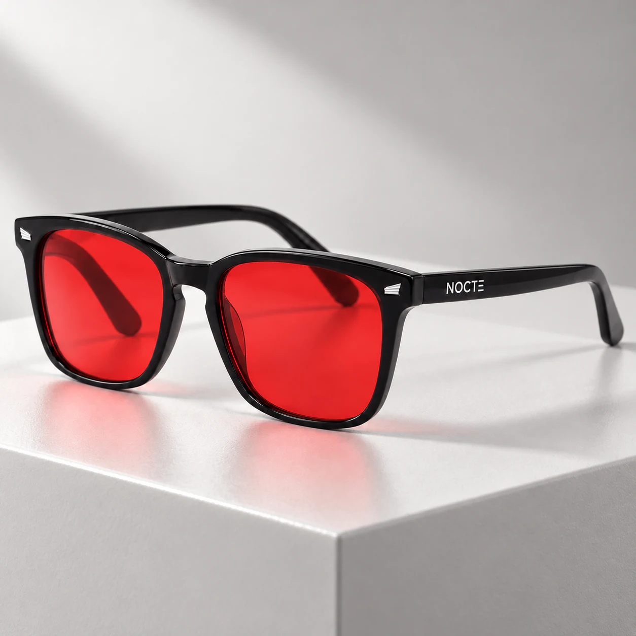 Lentes NOCTE con cristal rojo sobre un pedestal gris claro